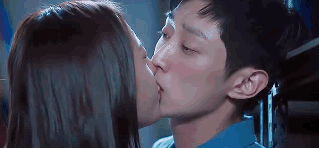 a man and woman are kissing in a room .