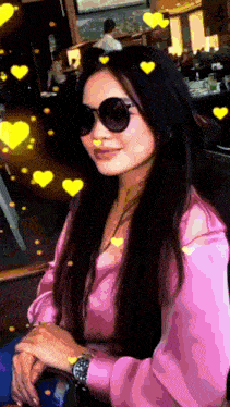 a woman wearing sunglasses and a watch is surrounded by hearts