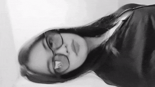 a black and white photo of a girl wearing glasses and a black shirt .