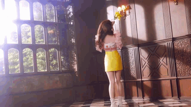 a woman in a yellow skirt and white boots stands in front of a window