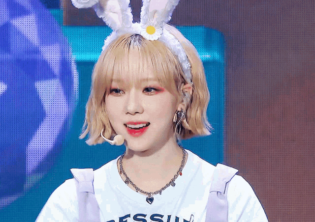 a girl wearing a bunny headband and a necklace with the word guess on it