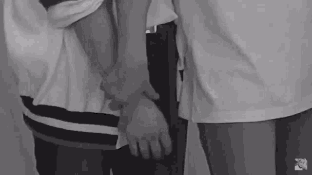 a black and white photo of a couple holding hands .