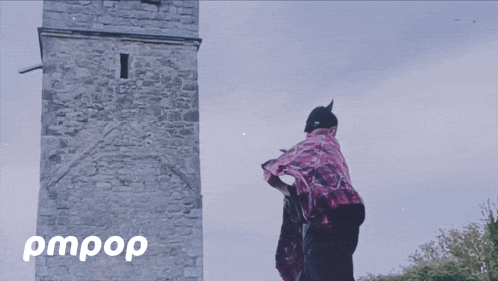 a person standing in front of a stone tower with the words pmpop written on the bottom
