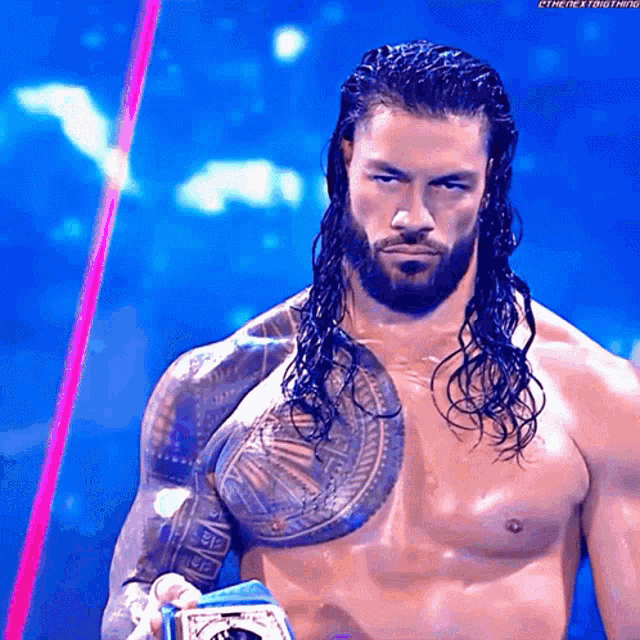 a man with long hair and a beard is holding a championship belt .