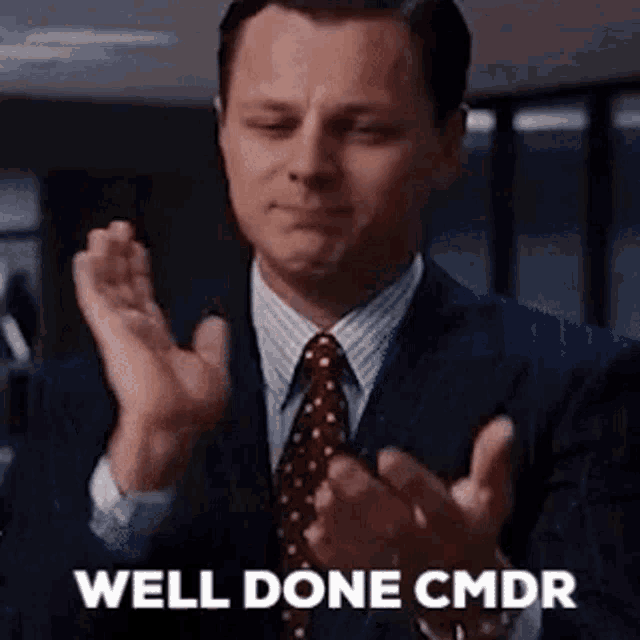 a man in a suit and tie is clapping his hands with the words `` well done cmdr '' .
