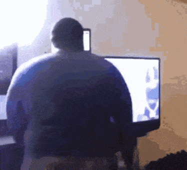 a man is standing in front of a computer monitor looking at something
