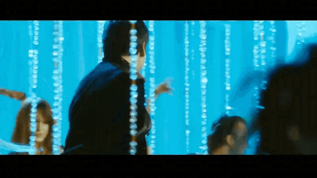 a man and woman are dancing in front of a blue wall