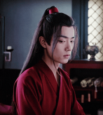 a young man with long hair wearing a red shirt