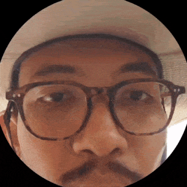 a close up of a man 's face with glasses and a hat on
