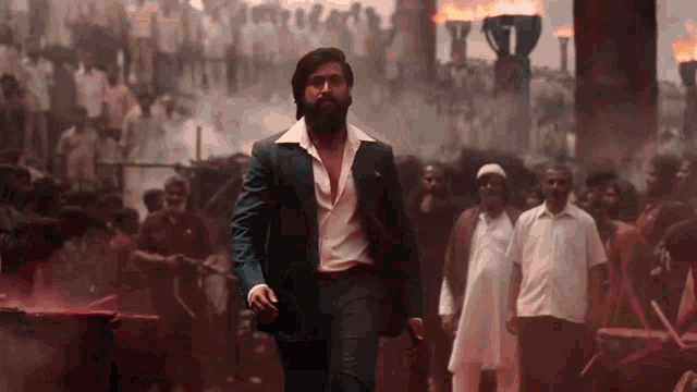a man with a beard is walking through a crowd of people in a suit .