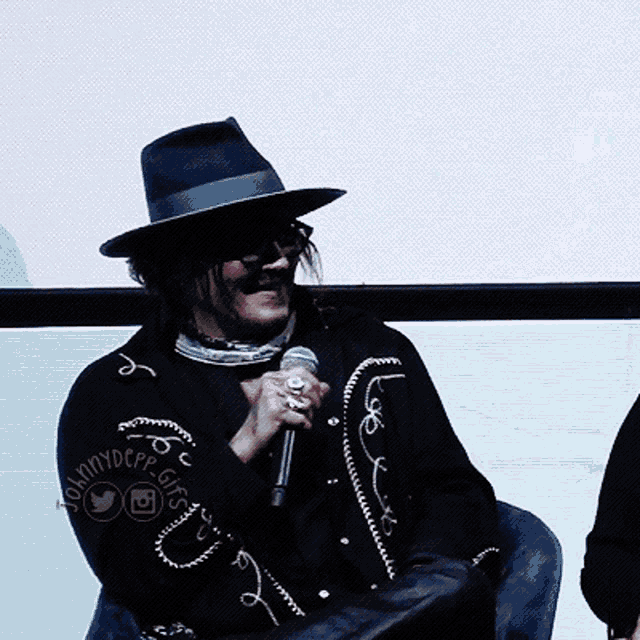a man wearing a hat and sunglasses is holding a microphone in front of a screen that says sunnydepp gifs