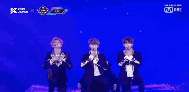 a group of young men are dancing on a stage with a mnet logo in the background .
