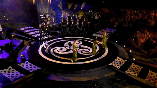 a group of people are dancing on a stage with a band behind them