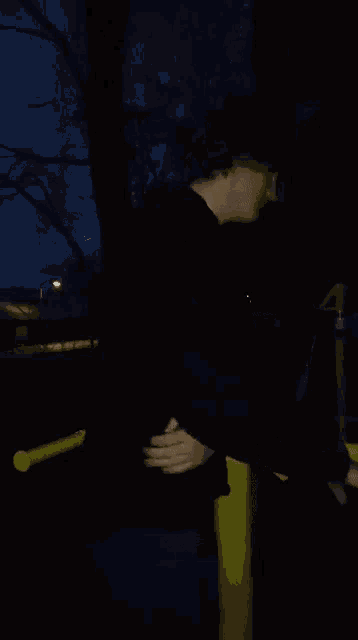a man in a black shirt is standing on a yellow railing at night
