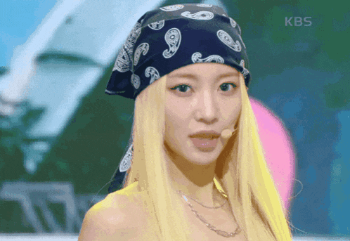 a woman with blonde hair wearing a bandana and a kbs logo on the bottom