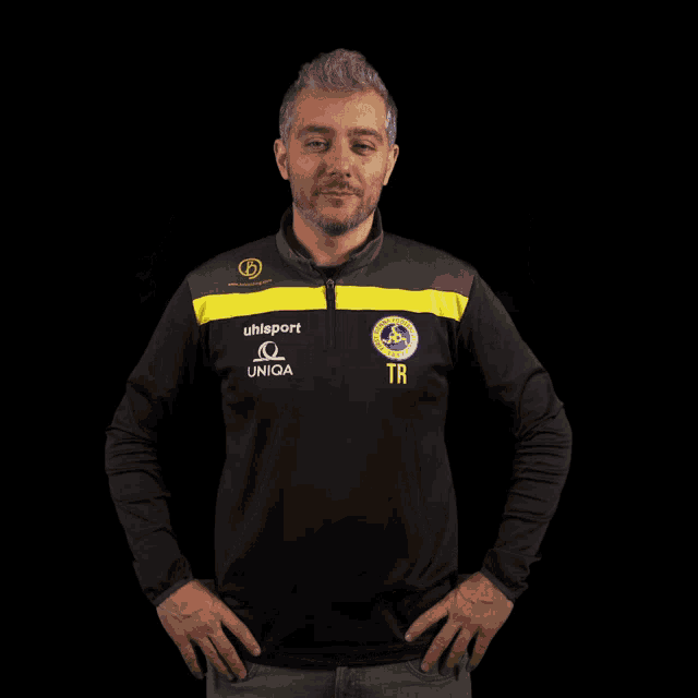 a man wearing a black and yellow shirt that says uhlsport