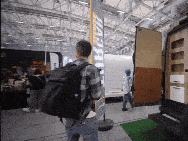 a man with a backpack stands in front of a sign that says benz on it