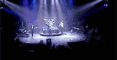 a group of people are standing on a stage in a dark room with a statue in the middle of the stage .