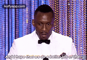a man in a suit and bow tie is giving a speech at an awards ceremony .