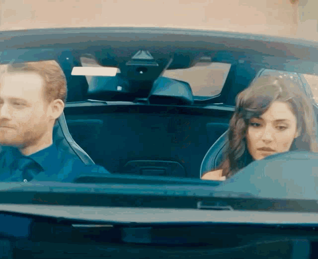 a man and a woman are sitting in a car looking at something