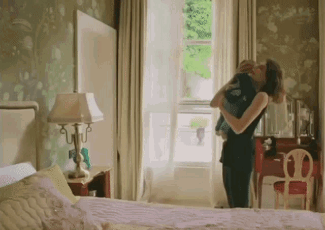 a woman holds a baby in her arms in a bedroom