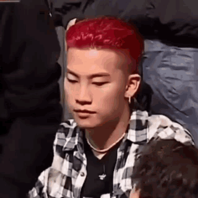 a young man with red hair is wearing a plaid shirt .