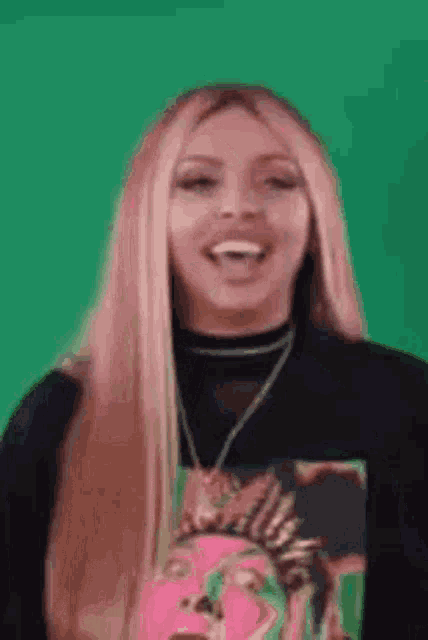 a woman with long blonde hair is laughing and wearing a black shirt with a picture on it .