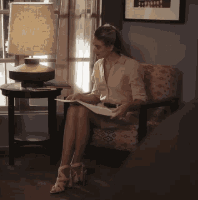 a woman is sitting in a chair reading a magazine