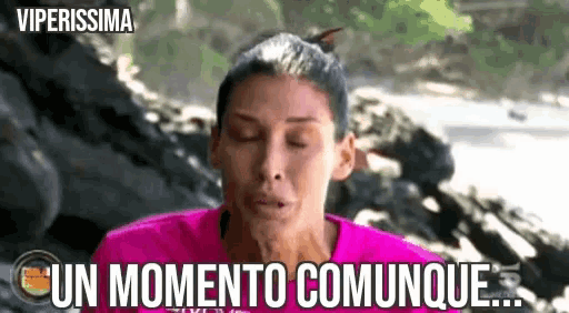 a woman in a pink shirt is making a face and says un momento commune