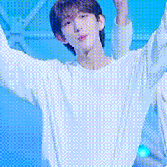 a young man in a white sweater is standing with his arms outstretched .
