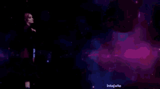 a woman in a white jacket is standing in a dark room with purple lights .