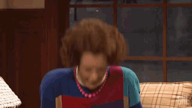 a woman in a colorful sweater is sleeping on a couch with the letters snl on the bottom