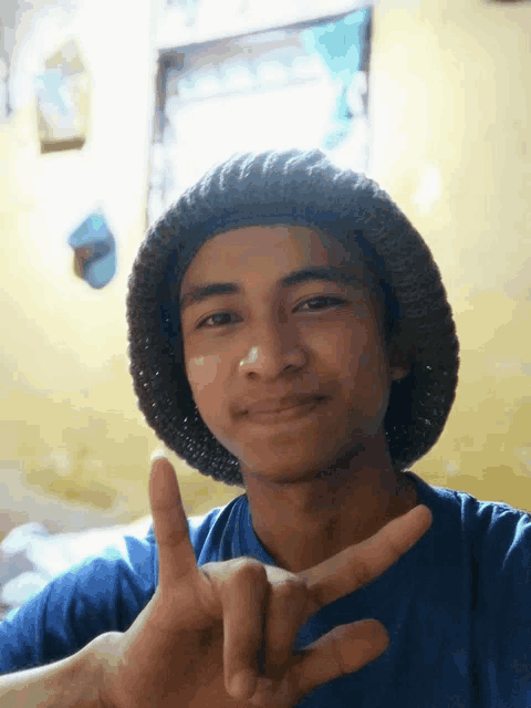a young man wearing a knitted hat makes a peace sign with his fingers