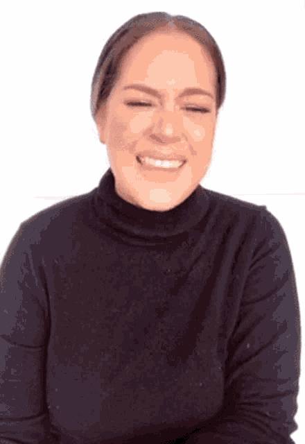 a woman in a black turtleneck sweater is smiling with her eyes closed .