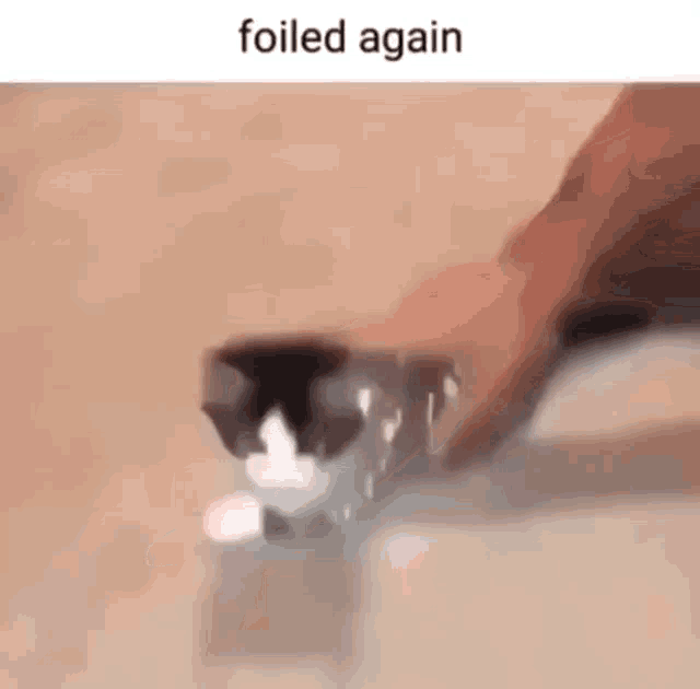a cat is playing with a piece of foil on the floor while a person holds it .