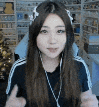 a girl wearing headphones and a headband is giving a thumbs up .