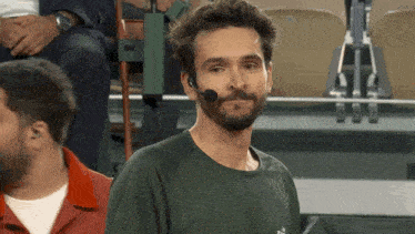 a man with a beard wearing a green shirt and a headset