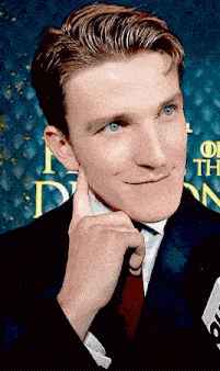 a man in a suit and tie is touching his ear with his hand .