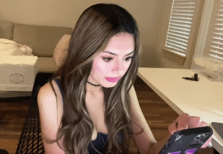 a woman sitting at a desk looking at a phone