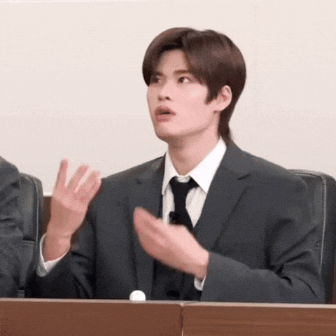 a man in a suit and tie is sitting in a courtroom .