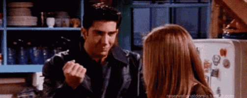 a man and a woman are standing next to each other in a kitchen and the man is making a fist .