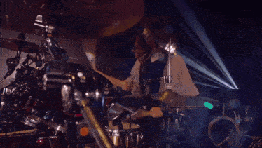 a woman playing a guitar in front of a drum set that says #tama