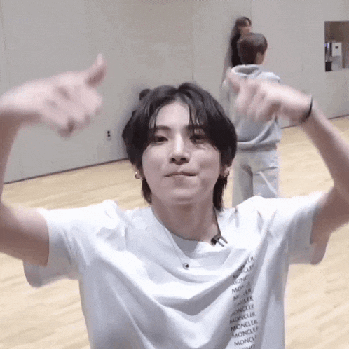 a young man wearing a white t-shirt is giving a thumbs up .