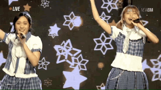 two girls singing in front of a live screen