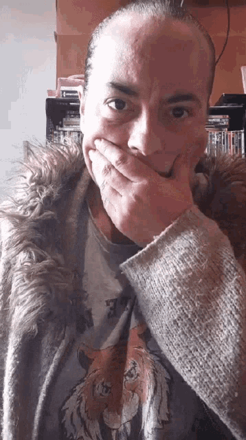 a man wearing a fur coat and a tiger shirt covering his mouth with his hand