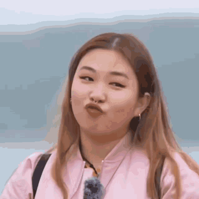 a woman in a pink jacket is making a face .