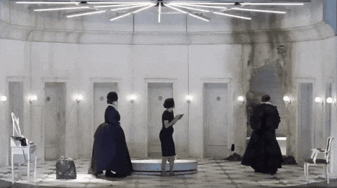 three women are standing in a room with a lot of doors and lights