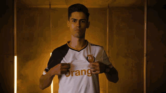 a man is holding up a shirt with the word orange on it
