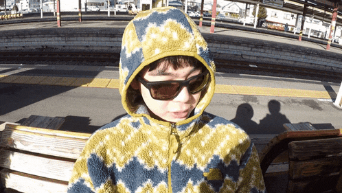 a young boy wearing sunglasses and a hooded jacket with the word north face on it