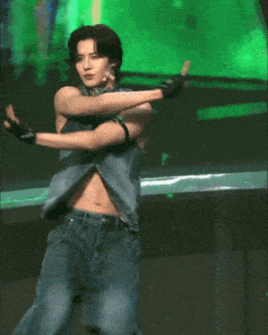 a man in a denim vest and jeans is dancing on stage